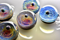 Galaxies Trapped in Tiny Glass PendantsGlass artist Satoshi Tomizu sculpts small glass spheres that appear to contain entire solar systems and galaxies. Planets made of opals, flecks of real gold, and trails of colored glass seem to spin and loop like