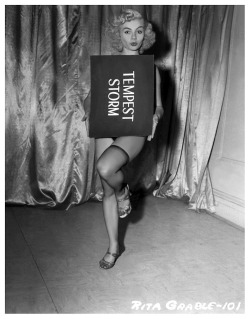 Rita Grable has fun with Tempest Storm&rsquo;s title card in this publicity still from Irving Klaw&rsquo;s 1956 Burlesque Film: &ldquo;BUXOM BEAUTEASE&rdquo;..