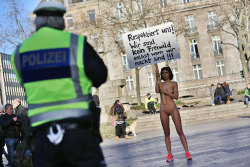 bintphotobooks:    A policeman looks on as performance artist Milo Moire holds up a poster reading “Respect us! We are no fair game, even when we are naked!!!” as she stands near Cologne’s landmark, the Cologne Cathedral, to protest on January 8,