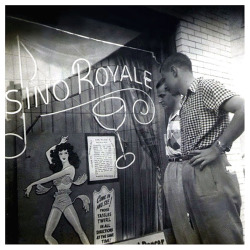 Vintage press photo from 1951 shows young males browsing the window details of the &lsquo;Casino Royale&rsquo;; a nightclub located in the French Quarter of New Orleans.. The venue was run by a popular local dancer named: Stormy (aka. Stacey Lawrence)..