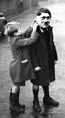 A young boy adjusts his friend’s Adolf Hitler mask during a game in King’s Cross, London, 1938.