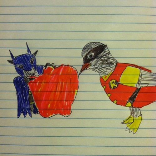 A bat and a robin dressed as Batman and Robin. The bat is eating an apple. 