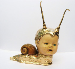 pobrecitaprincesa:Timmy is made up from an old, antique, very sad and beat up doll head, taxidermy giant snail shell, taxidermy raccoon penis bones for his antennas, some clay, some golden enamel paint.