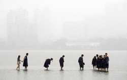 unearthedviews:Wuhan, China: Students in graduation robes stand on a stone bridge submerged by floodwaters on Donghu Lake  Darley Wong /Reuters