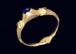 oakapples:  A 13th-century gold ring set with a sapphire that was found buried in Hatfield Forest, Essex. The design consists of a pair of dragons whose tails merge into two clasped hands. Around the hoop is an inscription in Lombardic script that reads: