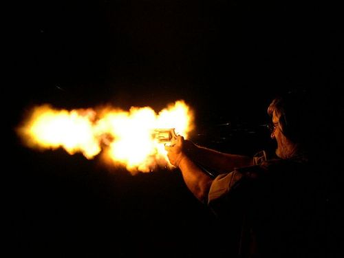 Muzzle flash from man firing handgun