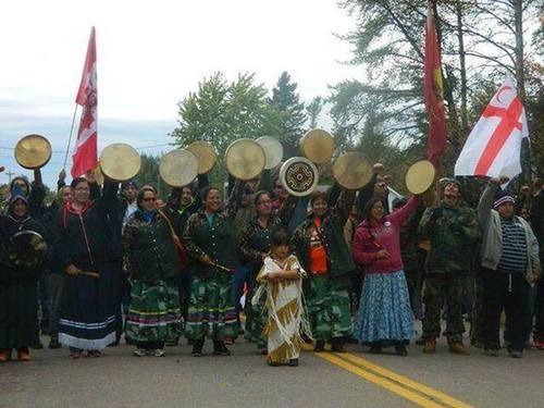 Photo of a group of Indigenous women holding flags and drums