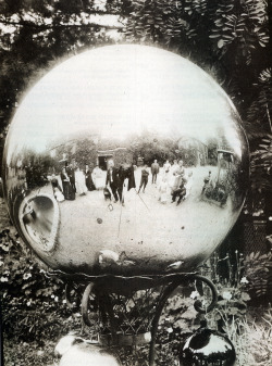 Une famille se prend en photo dans une ornementation de jardin en forme de globe poli dans les années 1910.