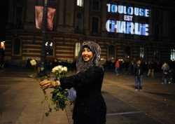stunningpicture:  A muslim girl distributing flowers in France at the site of the terrorism act  ^^^ Correction: this is clearly in Toulouse, as indicated by the projection on the top left of the photo. The terrorist attacks on Charlie Hebdo and the