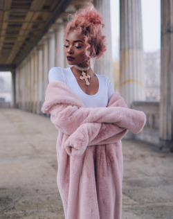 qcrip:  color-head:   Nyané Lebajoa   [3 photos of Nyané Lebajoa in a long pink fuzzy coat, pink pencil skirt, white t shirt, and rose gold heels with a cross necklace, pink hair, and glowing makeup (1) her arms crossed (2) Her looking down (3) Her