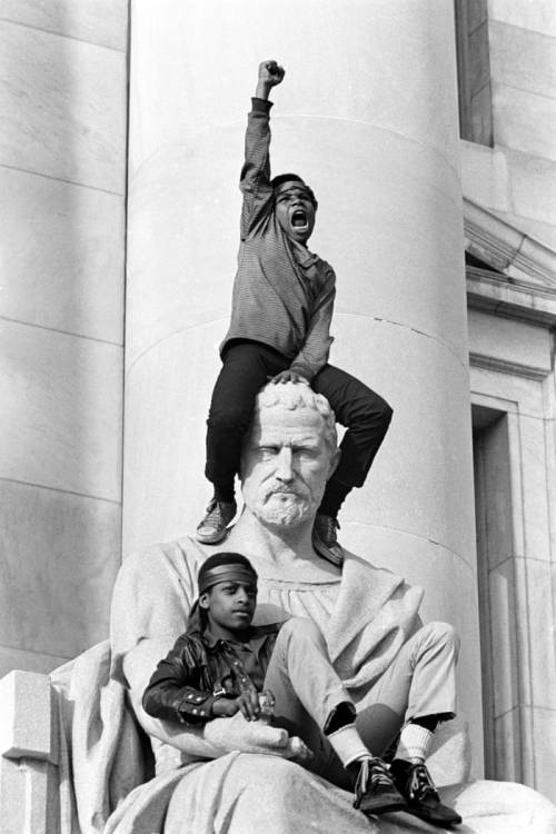 gnossienne:  A boy gives a raised fist salute in front of the New Haven courthouse during a demonstration by 15,000 people in 1970. Bobby Seale, chairman of the Black Panther Party, and Ericka Huggins were on trial along for murder. Both were acquitted