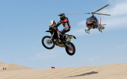 Airborne (Husqvarna rider Joan Barreda Bort of Spain competes in stage one of the Dakar Rally in Peru, between Lima and Pisco, as a helicopter flies overhead — 05January2013)