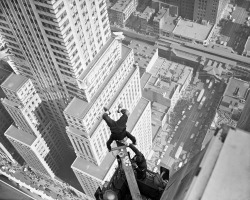 Alvin &lsquo;Shipwreck&rsquo; Kelly celebrates Friday the 13th by sitting on his head on a board stuck out from the 54th floor of the Chanin Building, and dunking doughnuts over Manhattan, 13 Oct 1939.