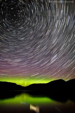 ohscience:   Star trails swirl through candy-colored auroras in a sweet new view of Sugar Lake in British Columbia, Canada, released this week. Taken in July, the long-exposure picture illustrates how stars seem to rotate around what’s known as the