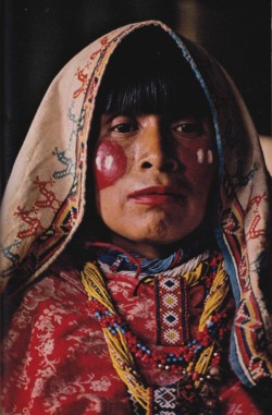 nationalgeographicscans:  June 1977  A painted prayer blooms on the cheeks of a Huichol woman, who uses lipstick to form a background for flower petals, symbols of fertility. Emblems of a sacred bird march across her headdress. In the solitude of the