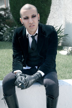 blacksheepgoths:  [image: a young Mexican person with shaved hair, lips piercings, and stretched ears. they sit on a curb with a cigarette in their hand, wearing a velvet blazer, with a vest, tie and white button up, as well as jeans, knee-high boots