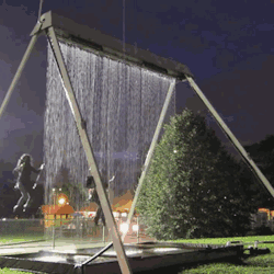 megamatttime:  livetomakeadifference:   Towering steel swing set holding arrays of mechanical solenoids that create a water plane falling in the path of its riders. Riders pass through openings in a waterfall created by precisely monitoring their path